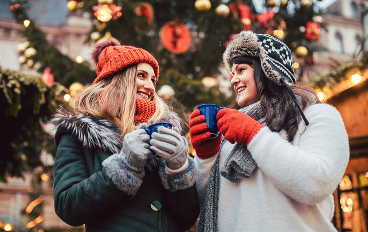 beste Freunde genießen Glühwein auf dem Weihnachtsmarkt